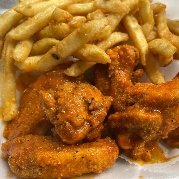 Close-up of Peppajak's buffalo wings and french fries, with visible seasoning on both.