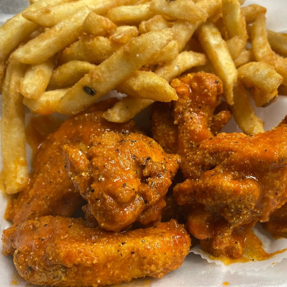 Close-up of Peppajak's buffalo wings and french fries, with visible seasoning on both.